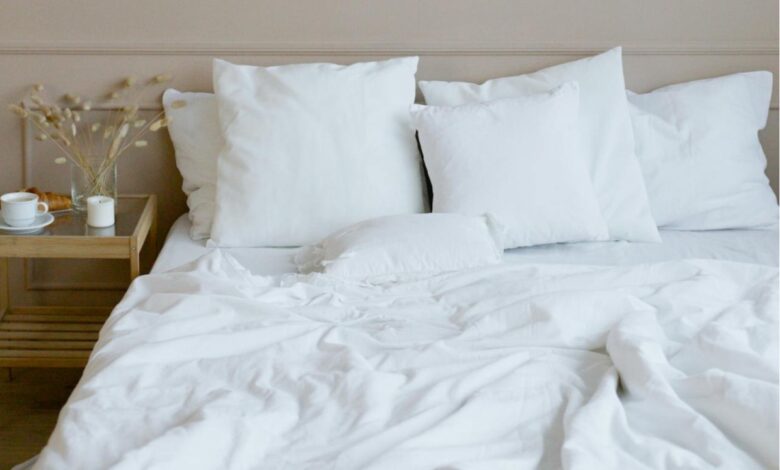 A bed made with cooling sheets for hot sleepers, featuring a light duvet and minimalist decor, conveying a fresh and airy feel.