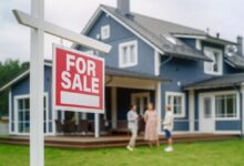 A couple talking to their realtor behind a "for sale" sign after the home inspection