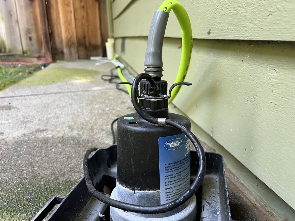 Close-up of a Superior Pump brand pump with green hose attached, located on an outdoor concrete path next to a residential home, Lafayette, California, May 29, 2024.