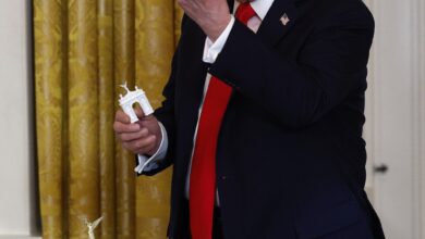 President Donald Trump holds models of a bow