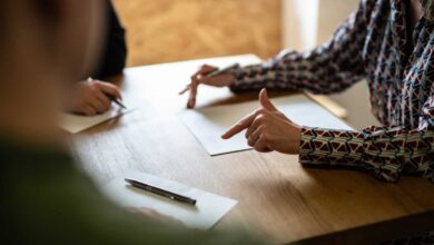 Three people sit around a table with partition action documents on it. One person is a partition lawyer who is explaining the documents to the other two people.