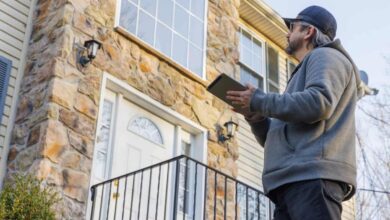 home appraiser standing outside a home looking up at exterior window