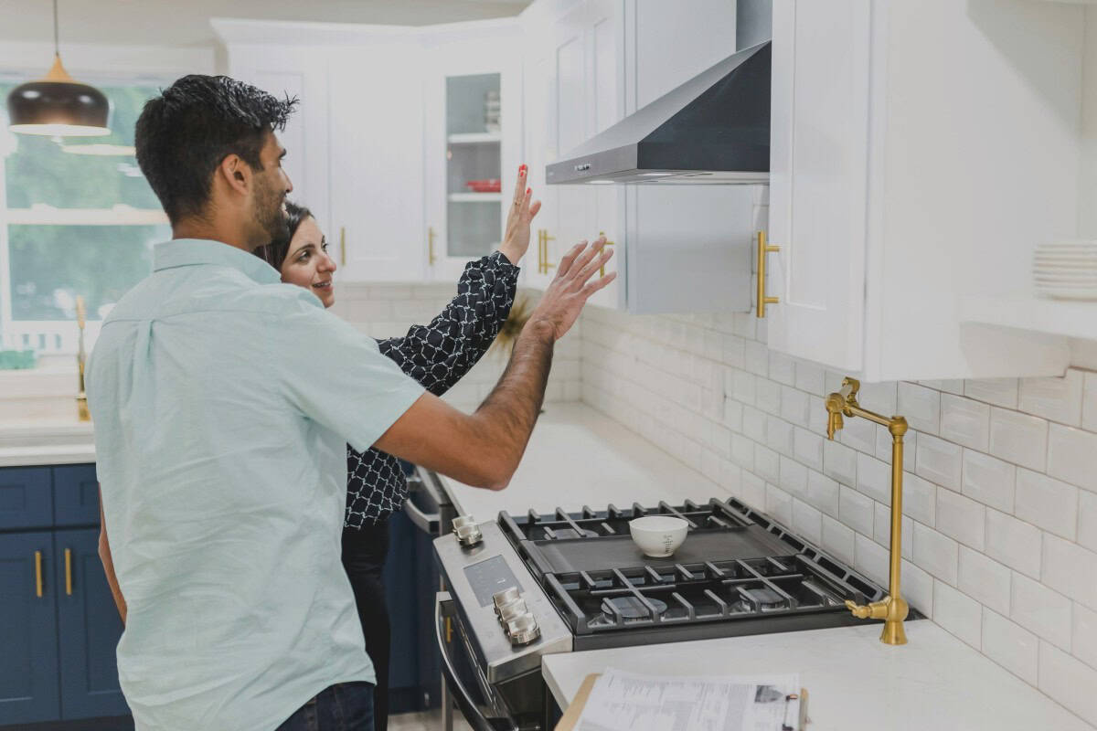 a man and woman inspect a kitchen